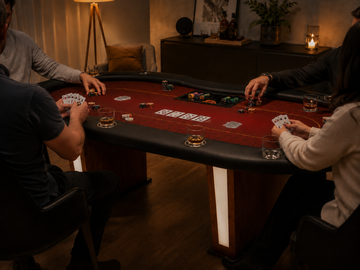 MRC Poker home game setup with players, cards, chips, and drinks around a red felt poker table in a warm indoor lounge.
